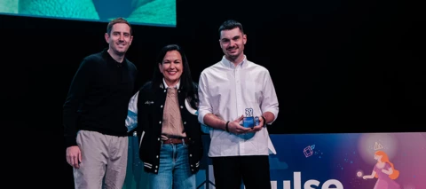 Image of three people, one holding a trophy at an award ceremony