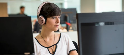 Person working with headphones and two screens in front of them