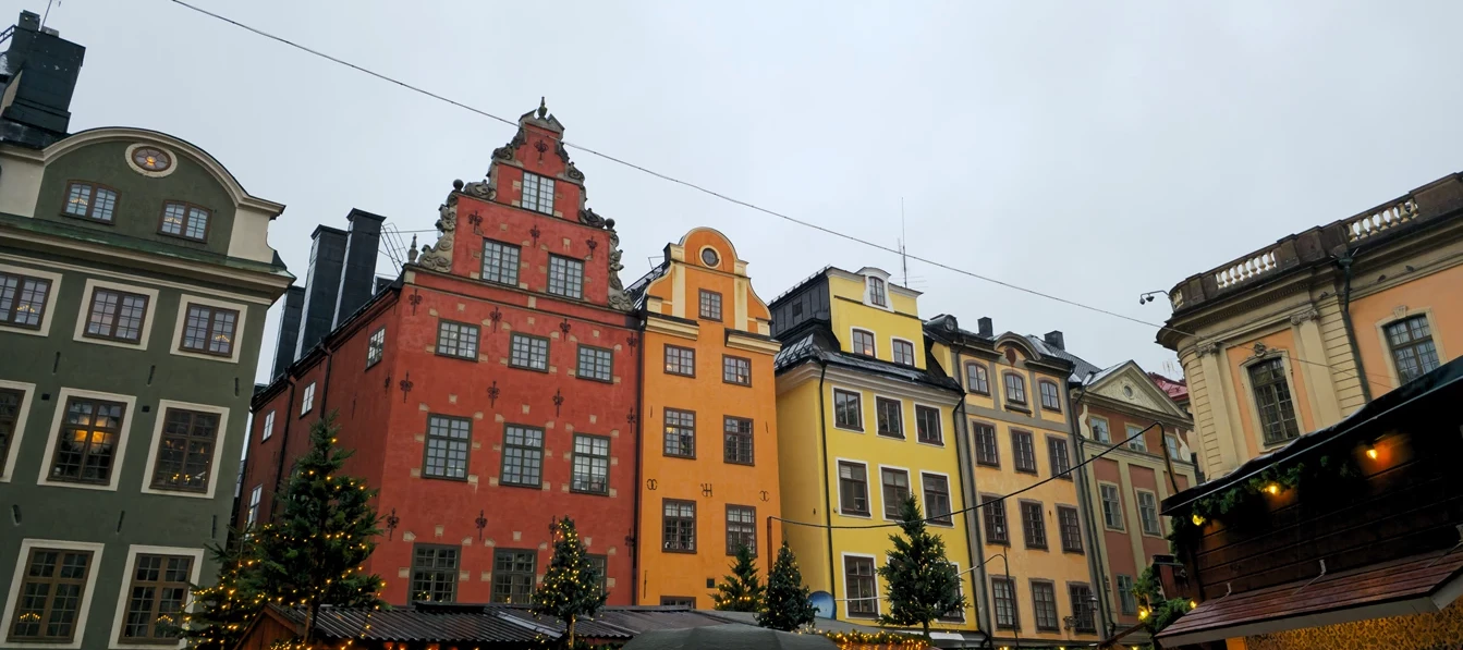 Frontansicht einer Häuserreihe mit hohen Häusern in verschiedenen Farben in einer Innenstadt in Schweden 