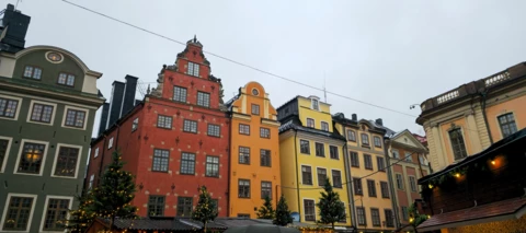 Frontansicht einer Häuserreihe mit hohen Häusern in verschiedenen Farben in einer Innenstadt in Schweden 