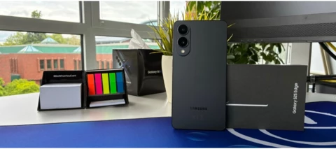 Das Samsung Galaxy S25 Edge, aufrecht stehend auf einem befüllten Schreibtisch. 