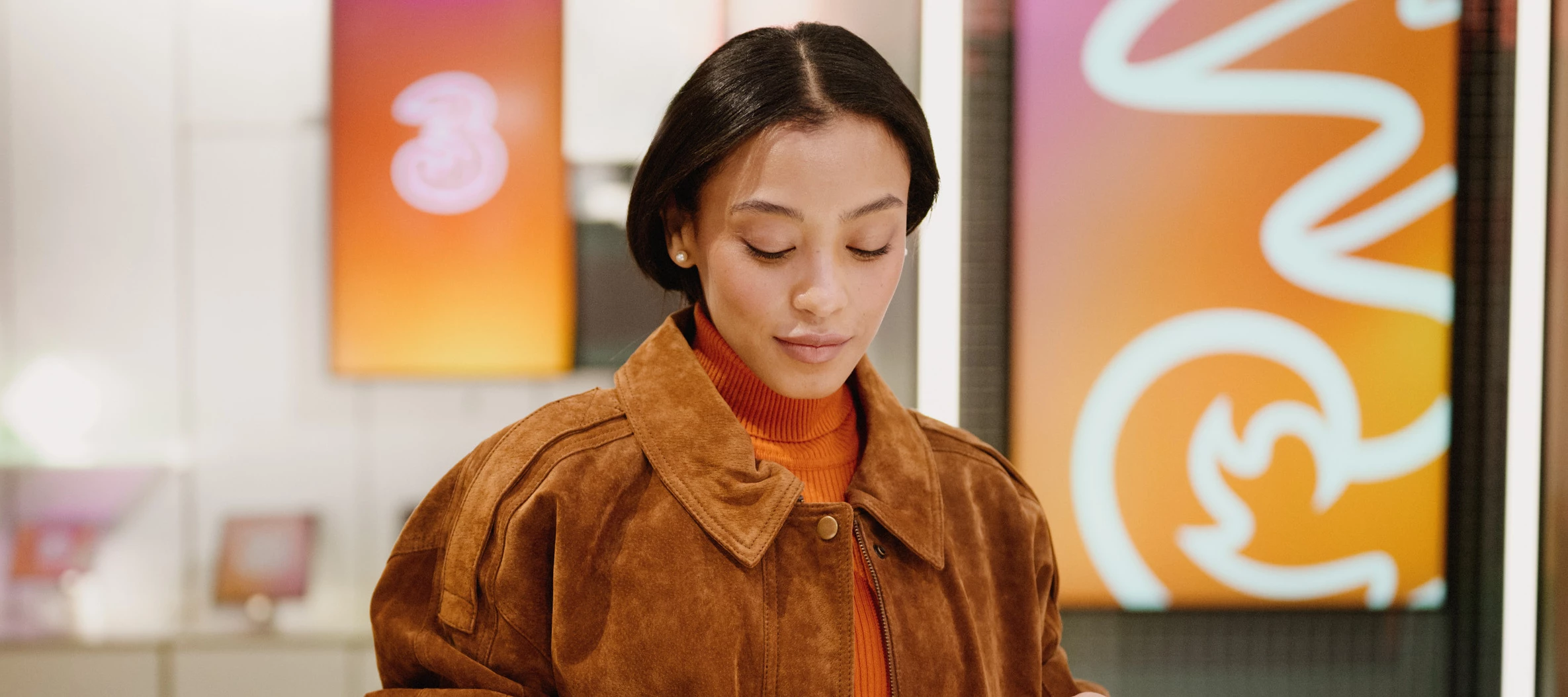 En person står i en Tre‑butik, med Tre‑logotypen synlig i bakgrunden.