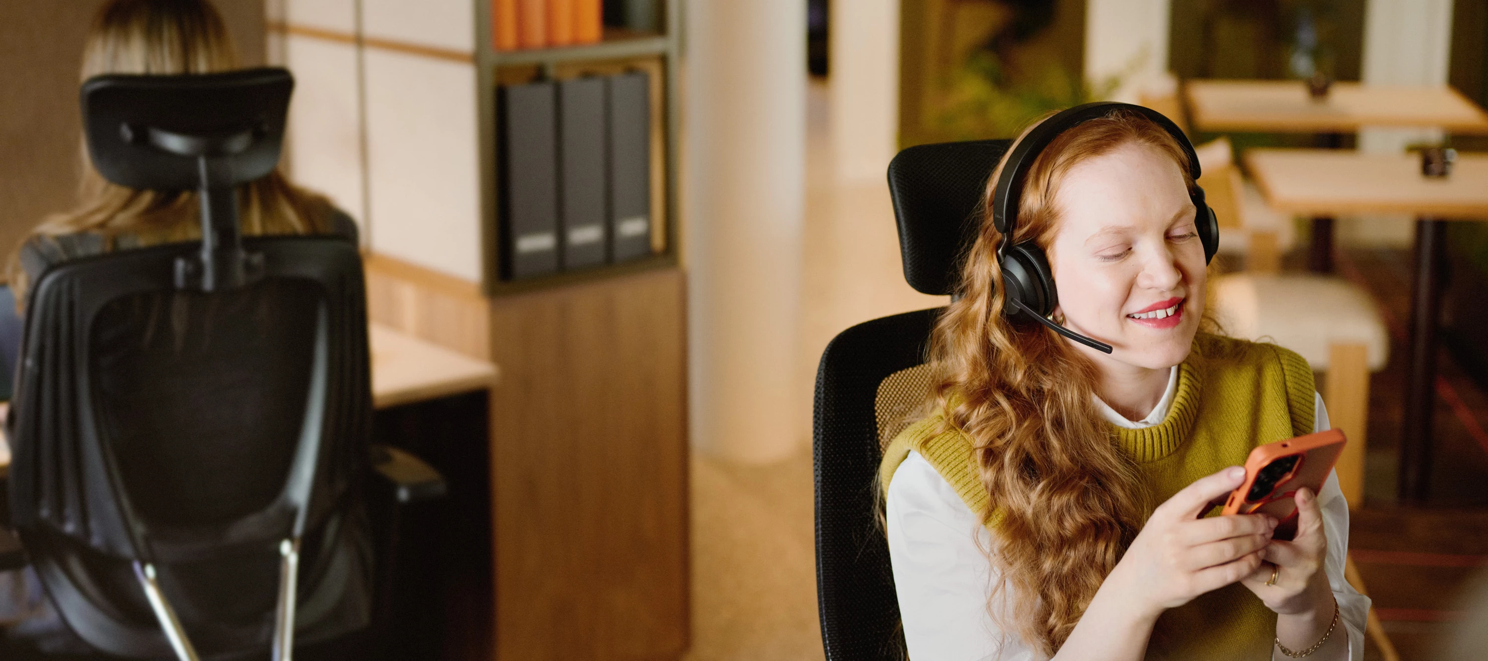 En person med headset sitter och jobbar vid ett skrivbord