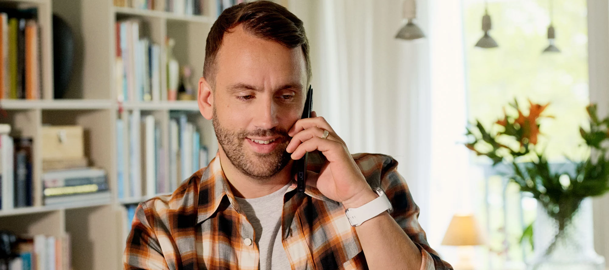Person sitter inomhus och pratar i telefon.