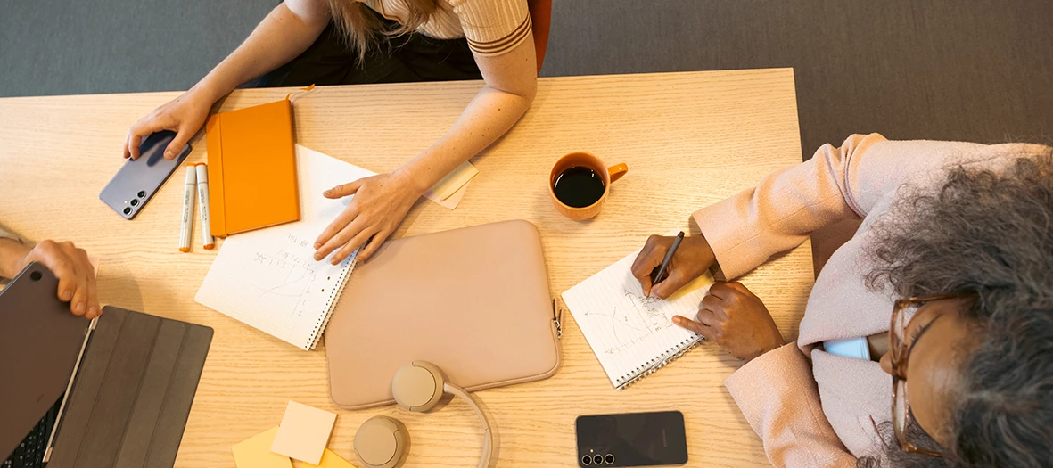 Två personer skriver anteckningar vid ett skrivbord