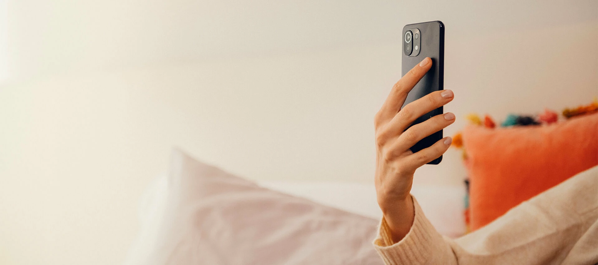 Hand som håller i mobiltelefon. Vit bakgrund.