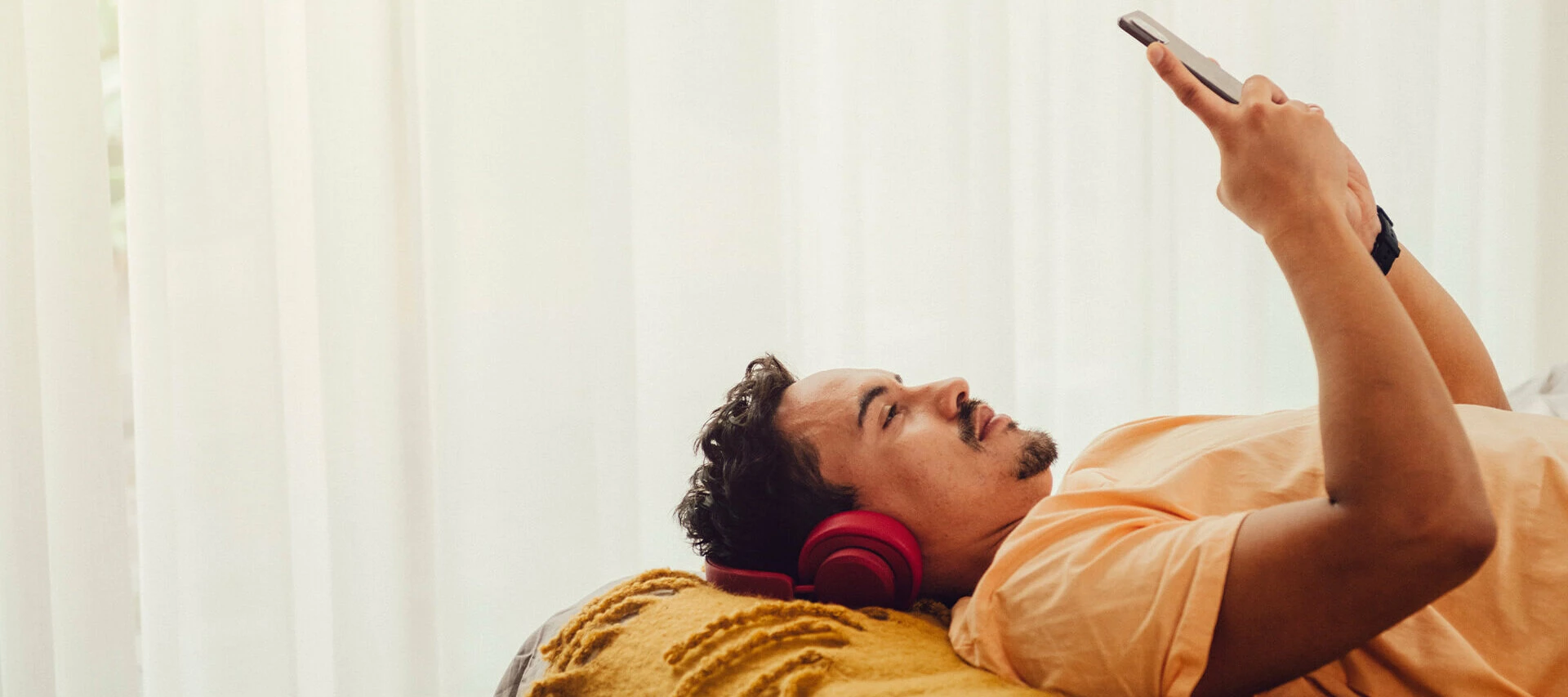 Person som ligger på en säng och kollar på mobiltelefonen