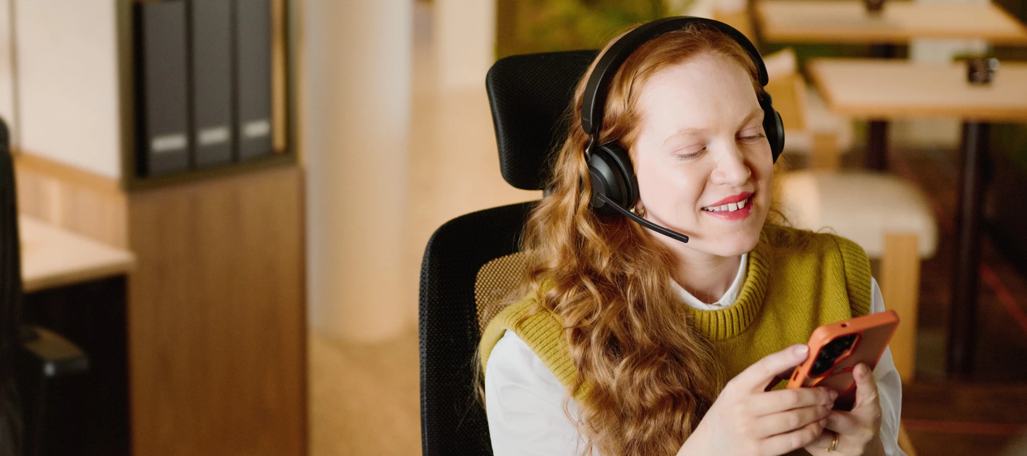 En kundservice agent sitter framför en laptop med ett headset och pratar